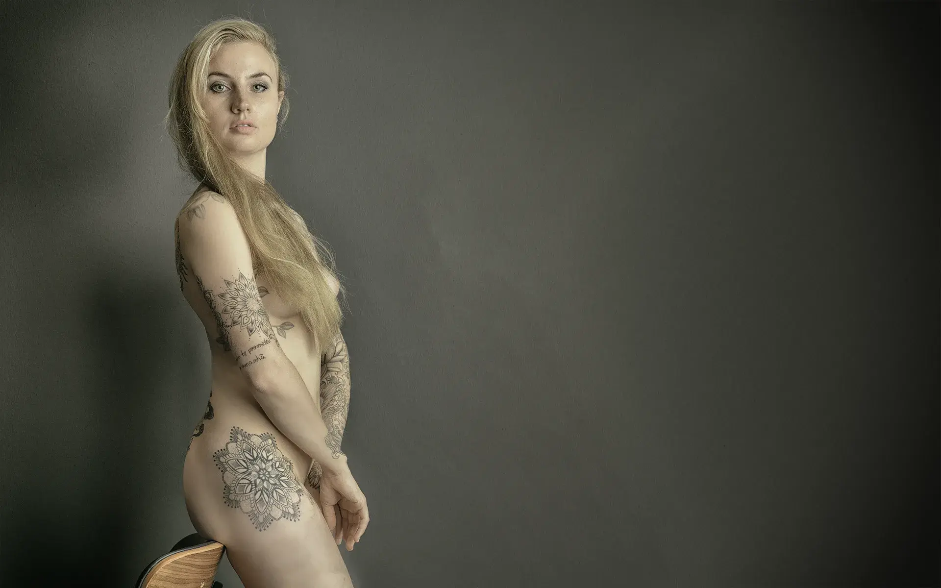 naakte vrouw kijkt op een bijna brutale manier recht in de camera. Van opzij gefotografeerd tegen een groenachtige achtergrond